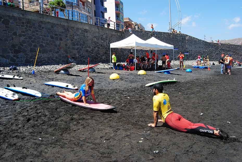 Un monitor enseña a una alumna las posiciones básicas del surf durante una de las clases de iniciación gratuitas. (Canarias Ahora).