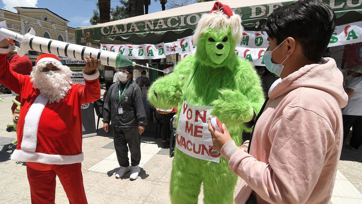 Ciudadanos bolivianos disfrazados hoy de Papá Noel y del Grinch, animan en este mes de navidad a inmunizarse contra la covid-19, en la ciudad de Cochabamba (Bolivia).