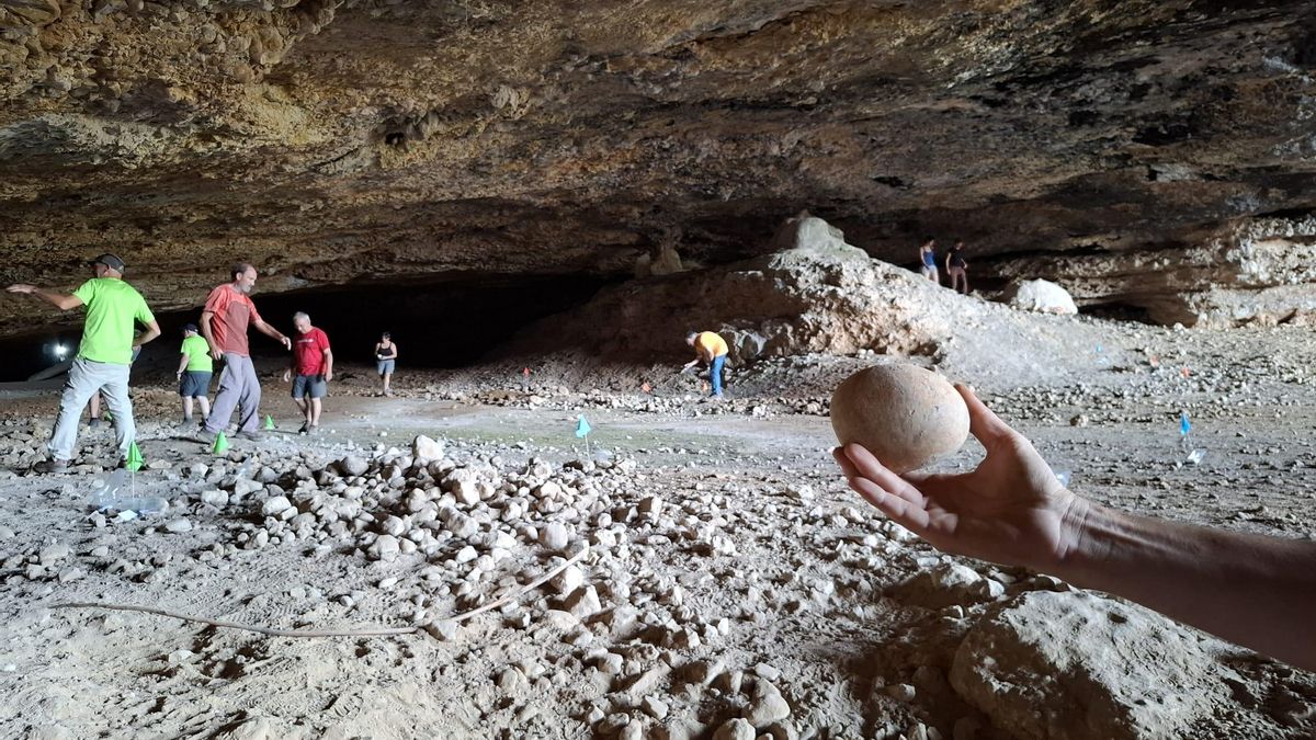 Más trabajos en la Cueva de Chaves, con uno de los cantos rodados localizados sostenido por una mano.