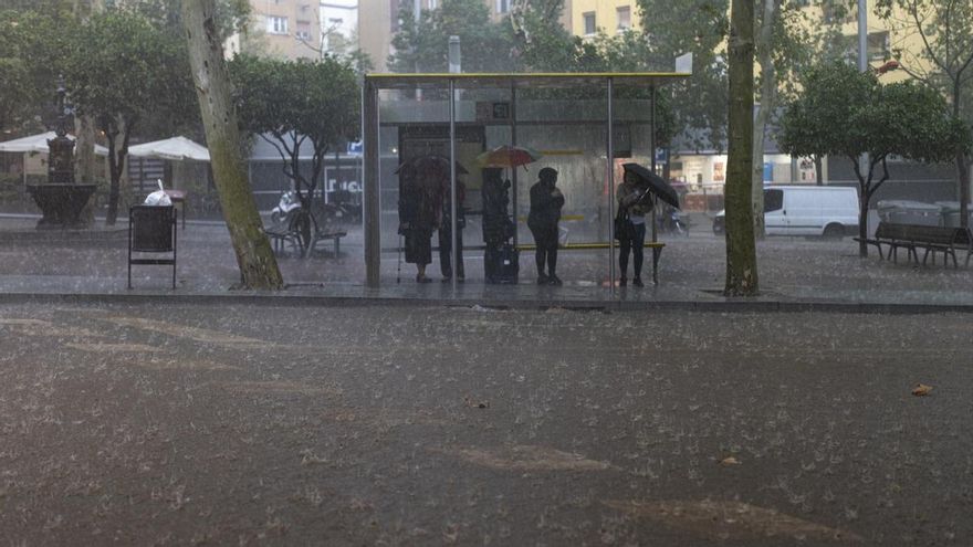 Varias personas esperan en la parada del bus durante la tormenta, a 30 de octubre de 2024, en Barcelona