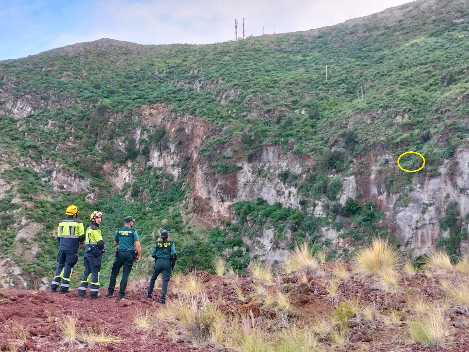 Bomberos  y agentes de la Guardia Civil observan en lugar  (marcado con un círculo) donde, en el entorno del Risco de La Concepción (Breña Alta), se encontraba la senderista rescatada con el helicóptero del Grupo de Emergencias y Salvamento (GES).