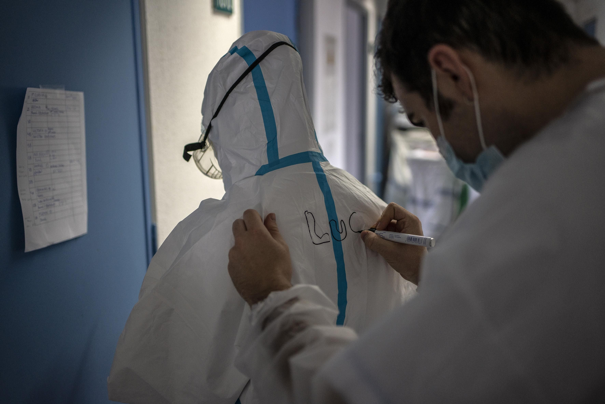 Un compañero de Lucía le escribe su nombre en el equipo de protección individual (epi). Cuando hay varias personas con epi es muy difícil reconocer quién es quién y lo hacen gracias a los nombres que se rotulan en la espalda.
