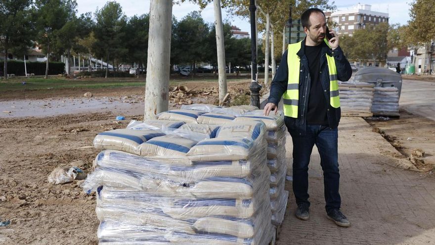 El alcalde de Aldaia, Guillermo Luján, conversa con por teléfono junto a varios palés de arena llevados a la localidad para proteger a las viviendas ante la posible llegada de una nueva DANA