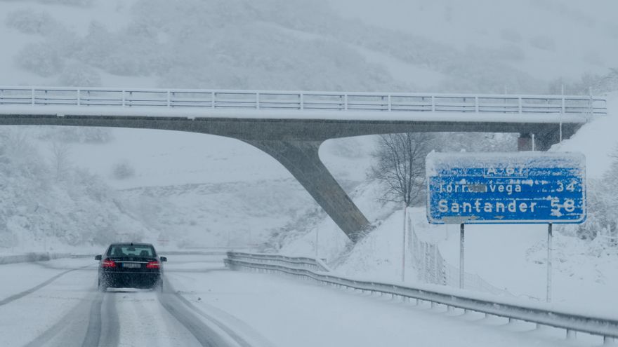 Un coche conduce por una carretera cubierta de nieve en Cantabria.