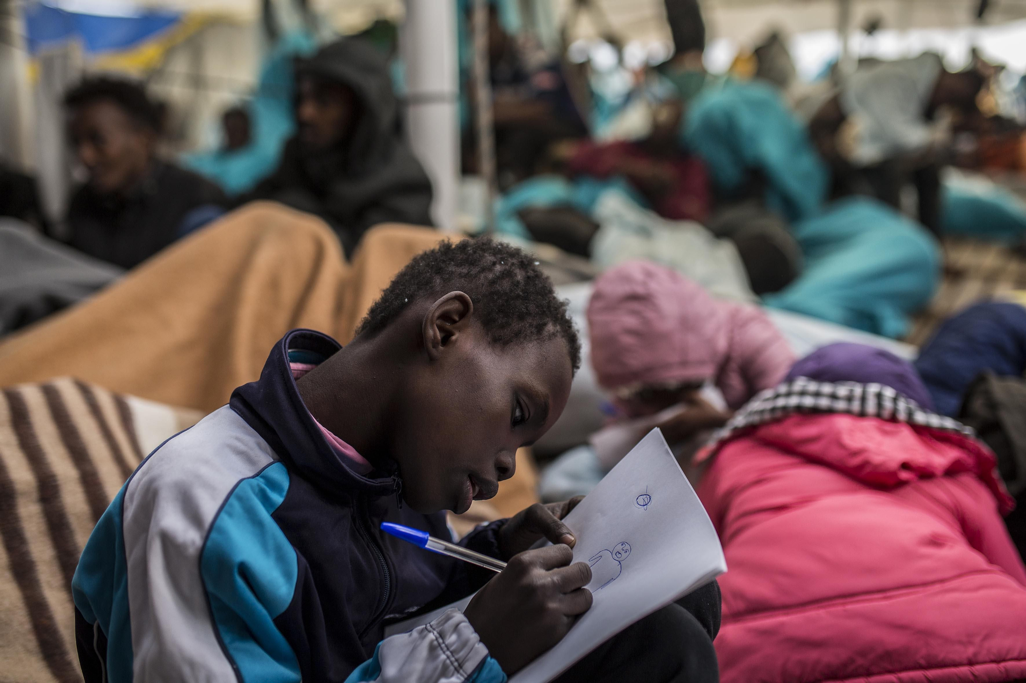Uno de los niños rescatados el pasado 21 de diciembre dibujando con un bolígrafo y un papel que le dio el capitán del barco / Olmo Calvo