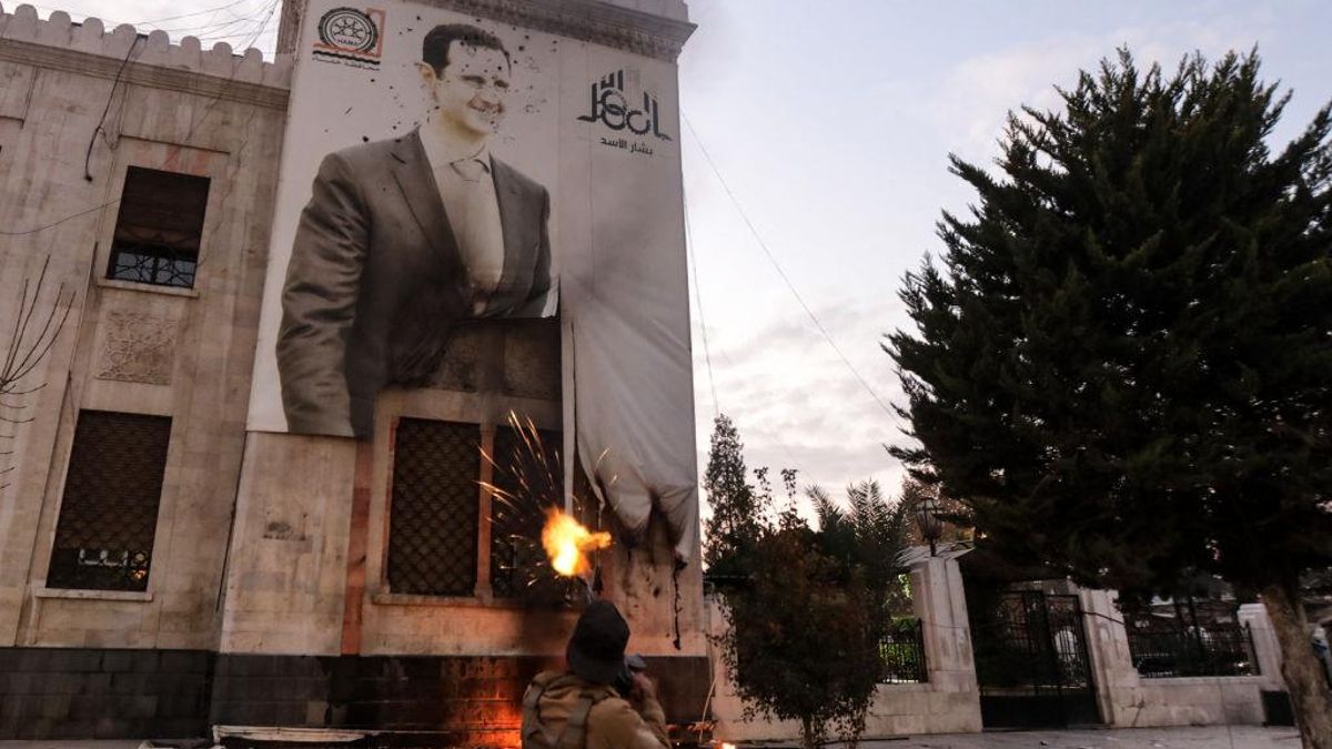 Un rebelde sirio dispara contra un gran cartel del presidente Bashar Al Asad en Hama, el 5 de diciembre de 2024.