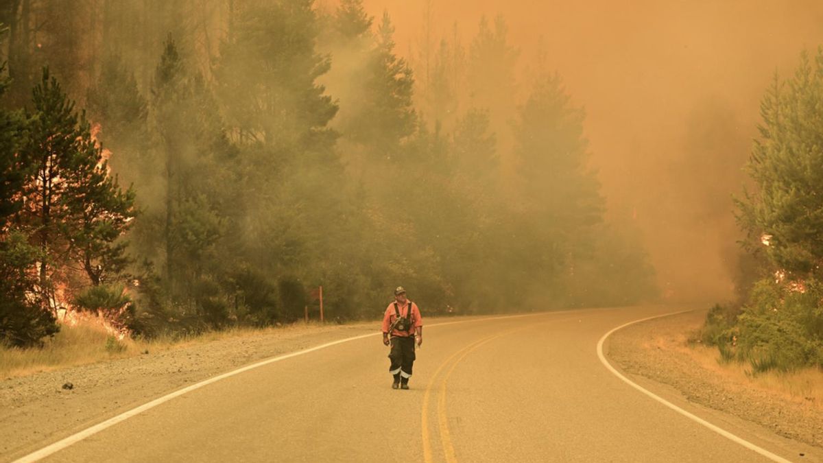 Un bombero camina por una carretera mientras los incendios forestales arden en El Hoyo, Patagonia, Argentina, el jueves 8 de enero de 2026.