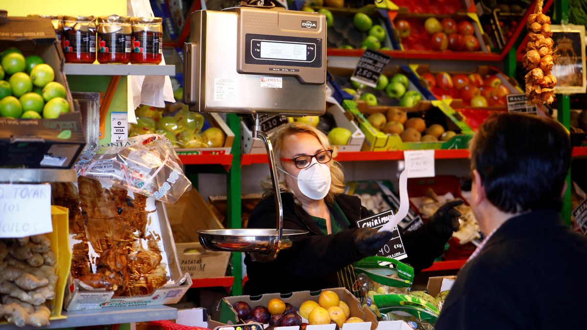 Una vendedora, protegida con mascarilla, trabaja en un mercado de abastos