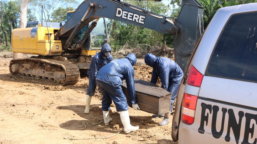 Trabajadores de una funeraria de Bolivia levantan un ataúd para llevarlo a una fosa recién cavada en Beni para víctimas de COVID-19.