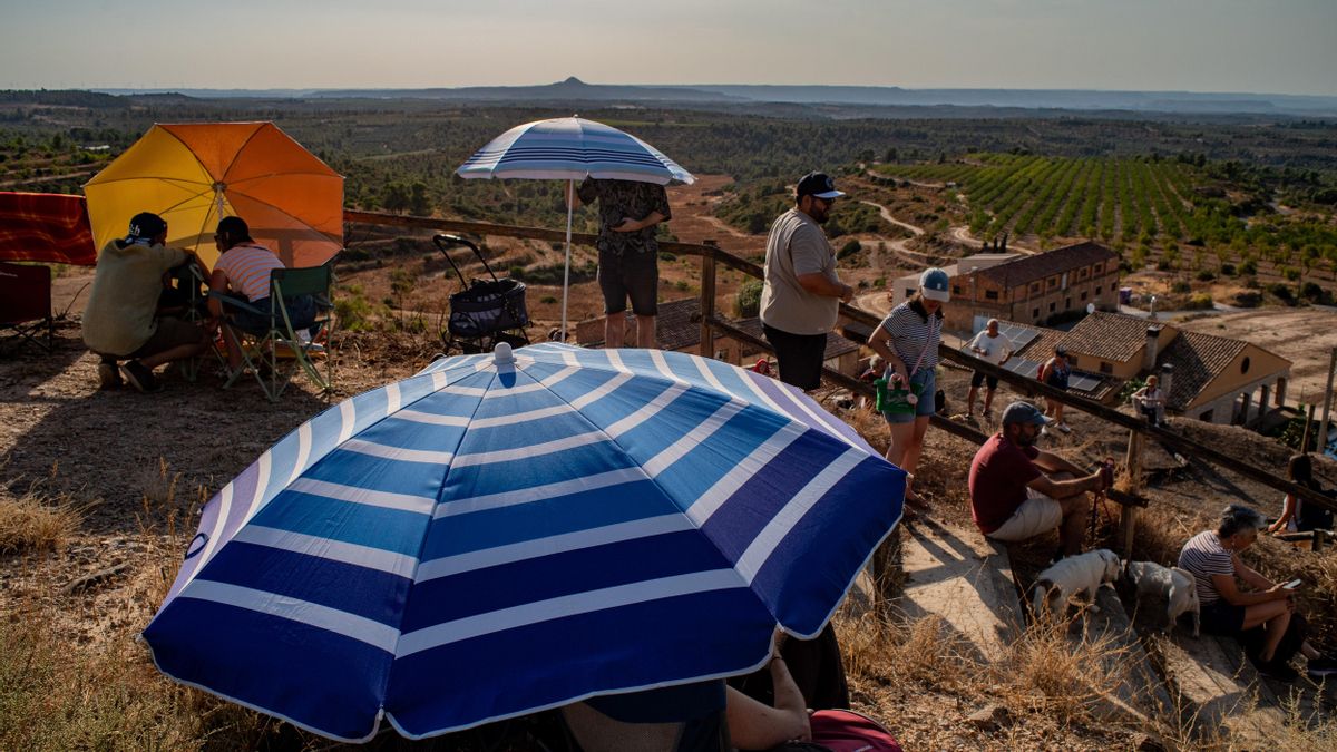 Varias personas reunidas en el punto más alto del pueblo de Llardecans ante el eclipse solar