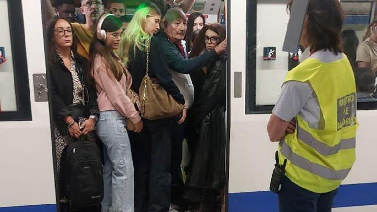 Una trabajadora de Metro de Madrid vigila cómo entran viajeros apelotonados en una estación de la línea 5.