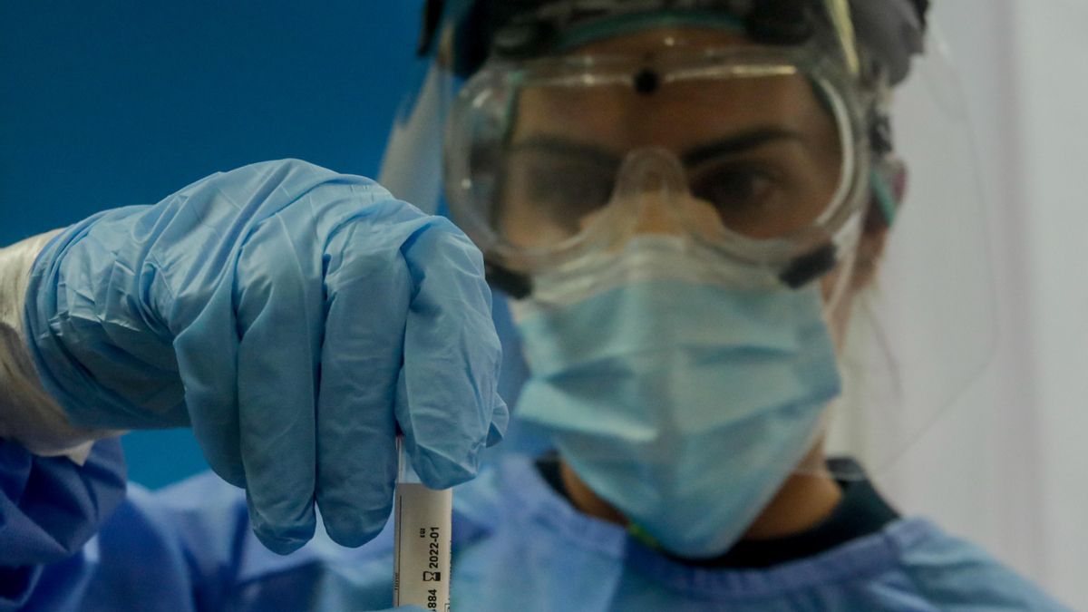 Archivo - Una trabajadora sanitaria sostiene una probeta con una prueba PCR