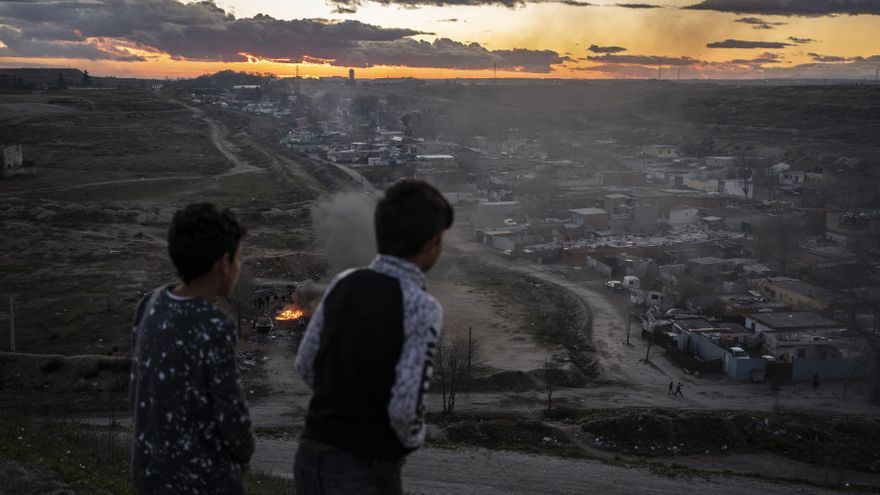 Dos niños observan el sector 6 de la Cañada Real desde un montículo de tierra cercano.