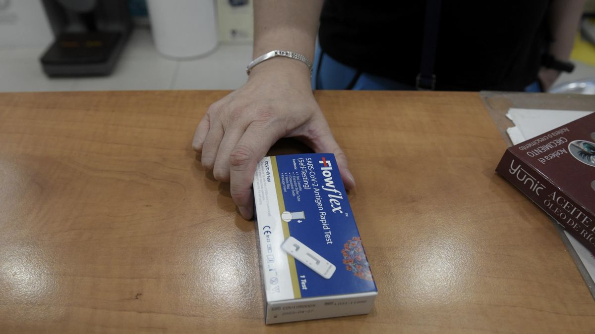 Un cliente enseña un test de antígenos de detección de la Covid en una farmacia.
