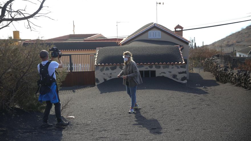 Periodistas junto a una casa enterrada por la ceniza