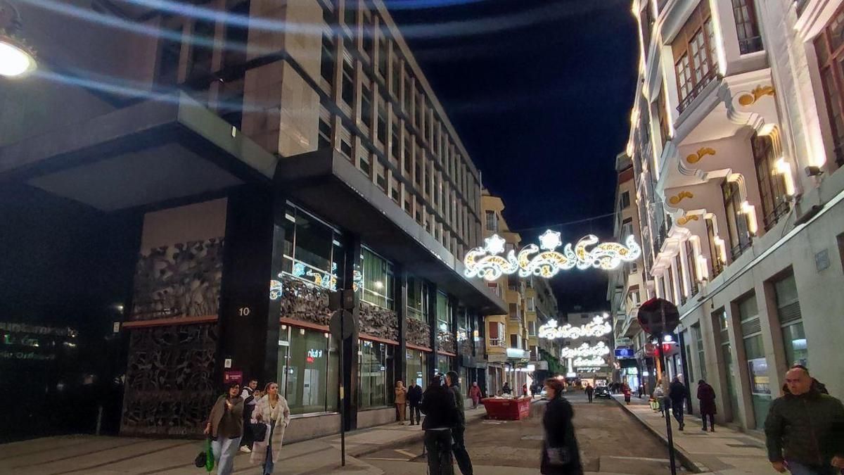 Viandantes bajo las luces de Navidad encendidas antes de tiempo en el centro de León.