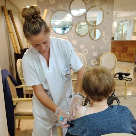 Una enfermera vacuna a una mujer mayor de 60 años en Asturias.