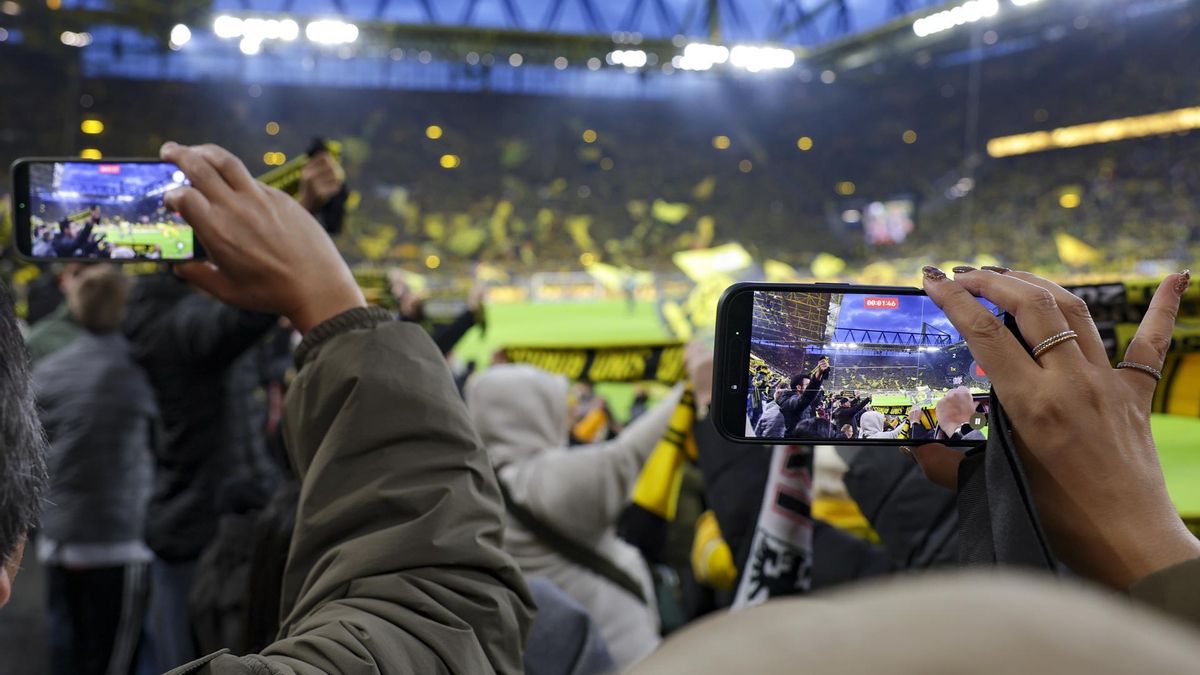 Los aficionados utilizan sus teléfonos móviles antes del partido de fútbol de la Bundesliga alemana entre el Borussia Dortmund y el Eintracht de Fráncfort, celebrado en Dortmund (Alemania), el 24 de octubre de 2026
