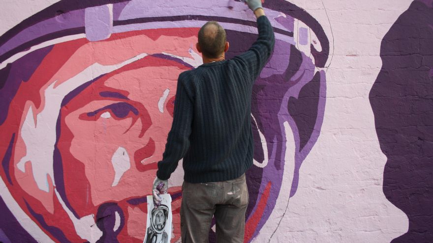 Mark pinta el casco de Valentina Tereshkova con una imagen de la cosmonauta soviética en la mano