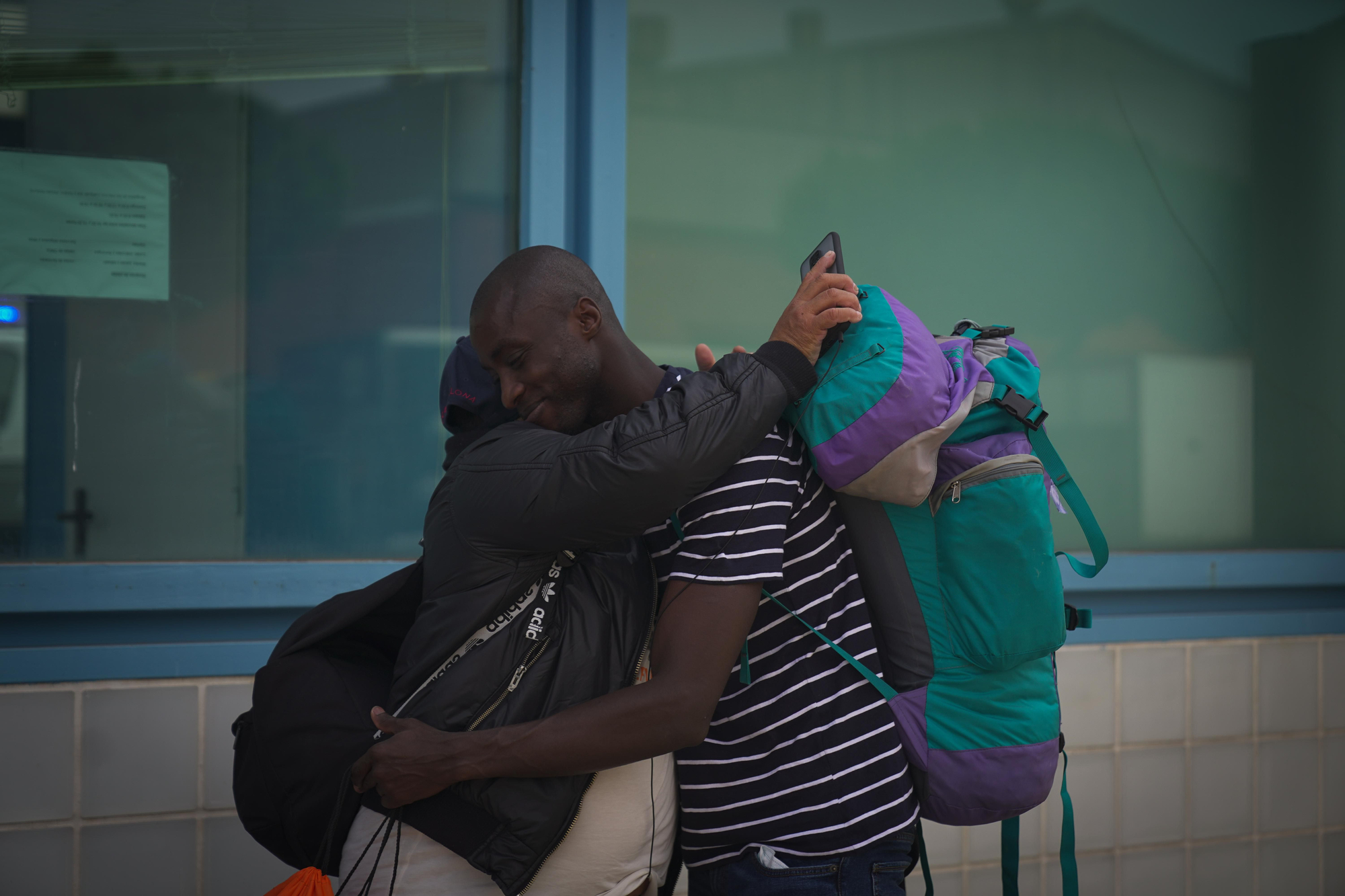 Dos internos se abrazan tras conseguir la libertad frente al Centro de Internamiento de Extranjeros de Barcelona