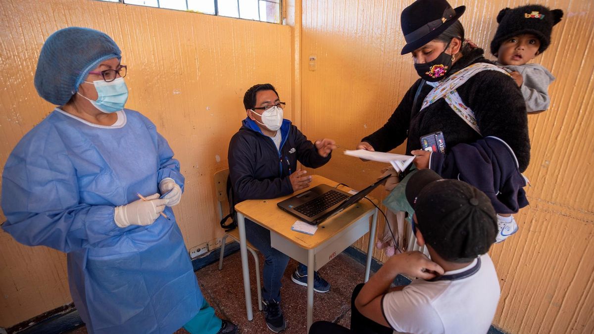 Un padre de familia registra los datos de su hijo antes de que le apliquen una dosis de la vacuna contra la covid-19 durante una jornada de vacunación a niños de 6 a 11 años, hoy, en un colegio de Quito (Ecuador).