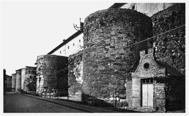 Calle de Ramón y Cajal en los 60 con las dos torres de la muralla aún sin desmochar y con la caseta donde guardaban los carros los barrenderos hasta los años 80.