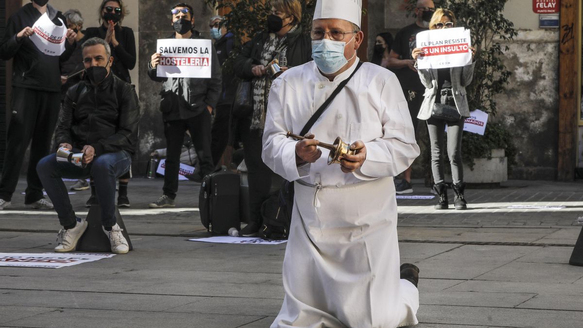 Un hombre con uniforme de cocinero se arrodilla durante una manifestación de hosteleros valencianos frente a las puertas del Palau de la Generalitat