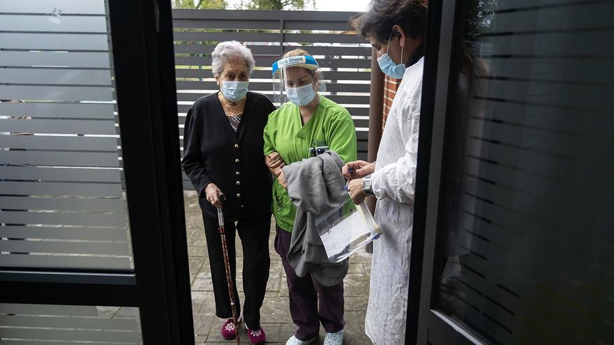 El director del centro sujeta la puerta mientras Leticia (la trabajadora) entra con una residente.