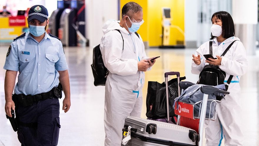 Viajeros con trajes de protección llegan al aeropuerto Internacional de Sídney (Australia).