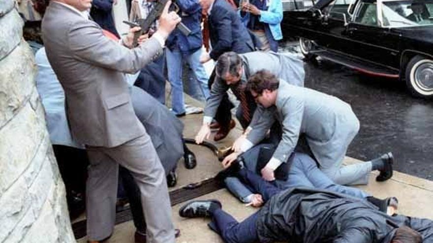 Agentes del Servicio Secreto cubren al secretario de prensa James Brady y al agente Thomas Delahanty durante el intento de asesinato de Reagan.