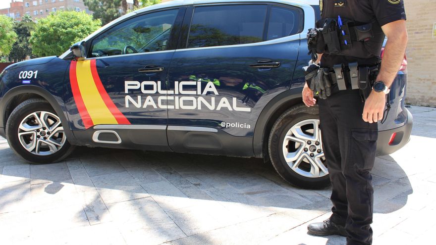 Agente de la Policía Nacional en una imagen de archivo junto al coche patrulla.
