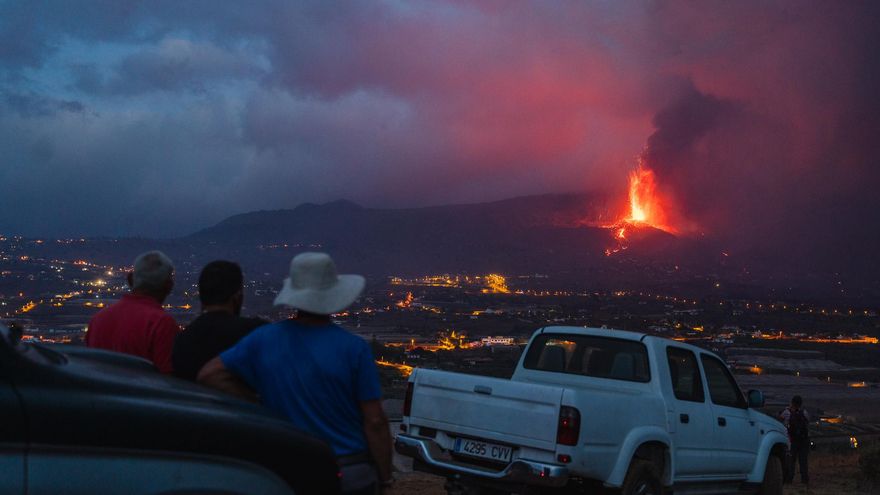 Tres personas observan la erupción volcánica en La Palma.