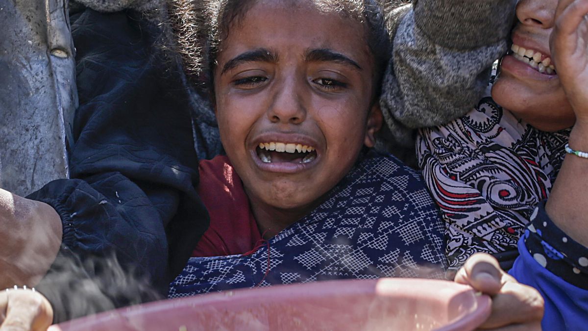 Una niña palestina desplazada internamente llora con un recipiente en las manos mientras espera para recibir alimentos. EFE/EPA/MOHAMMED SABER