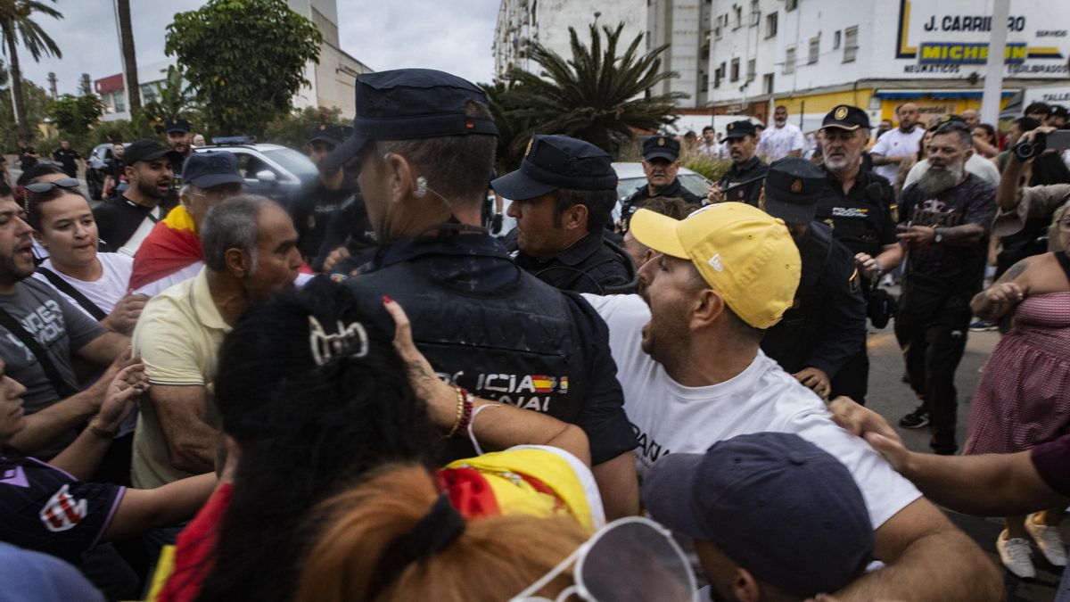 Agentes de la Policía Nacional tratan de contener el avance de las decenas de manifestantes que trataban de agredir a los activistas en el puerto de Ceuta.