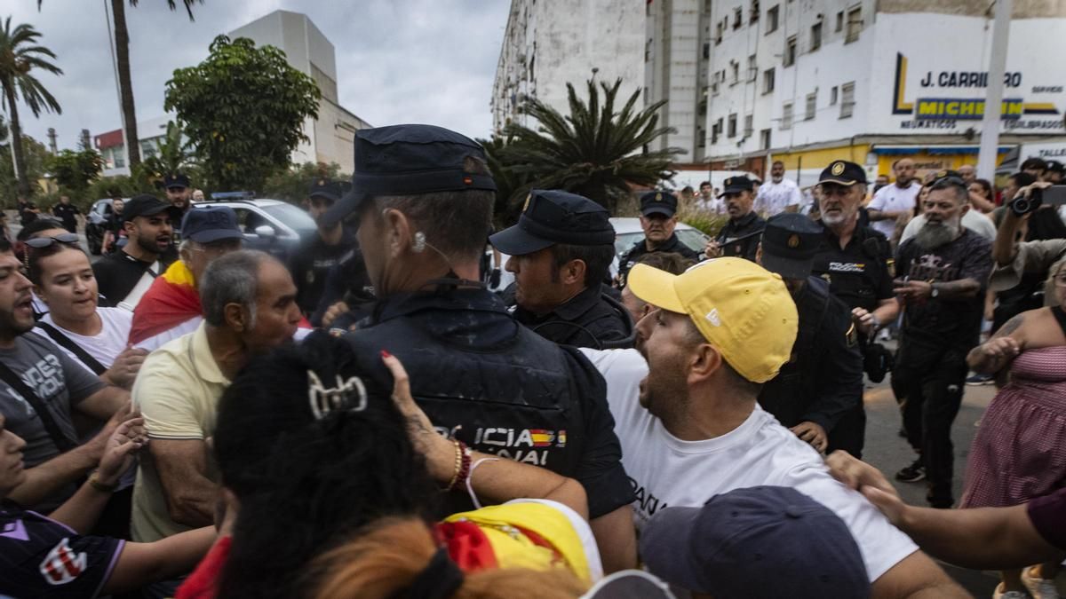 Agentes de la Policía Nacional tratan de contener el avance de las decenas de manifestantes que trataban de agredir a los activistas en el puerto de Ceuta.
