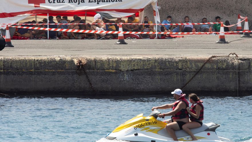 Migrantes en el suelo del muelle de Arguineguín, donde pasarán la noche a la espera de plazas de acogida