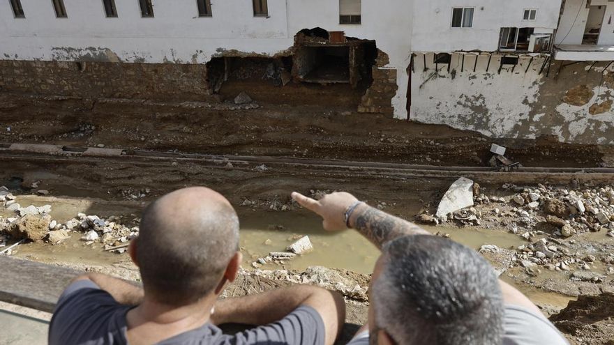 Varias personas analizan los daños a una vivienda causados por la DANA en Chiva.