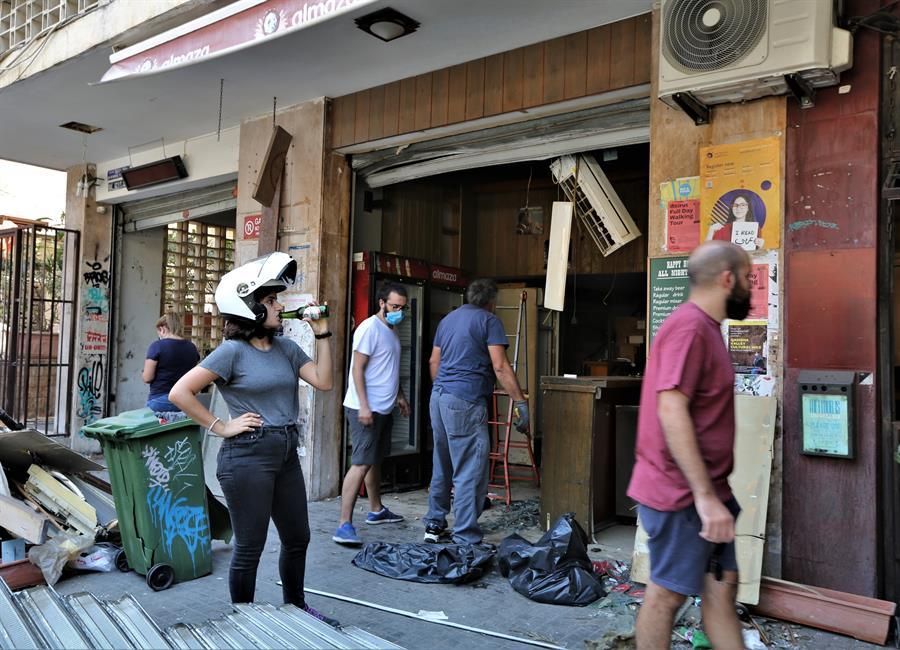 Jóvenes beben cerveza mientras limpian los daños de su pub.