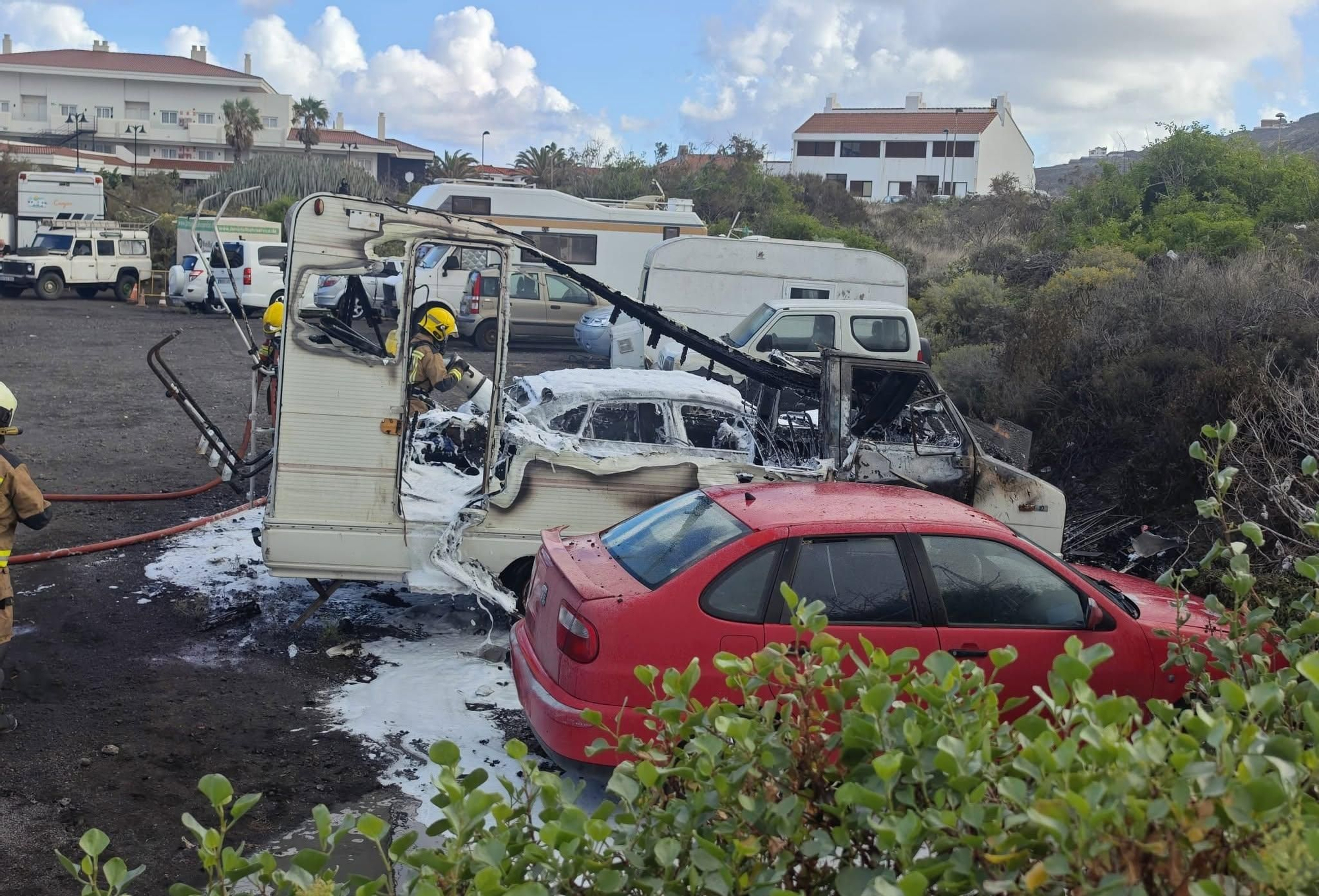 Tres bomberos en las tareas de extinción del incendio de una autocaravana en Los Cancajos  (Breña Baja) que afectó a dos  coches estacionados a ambos lados.