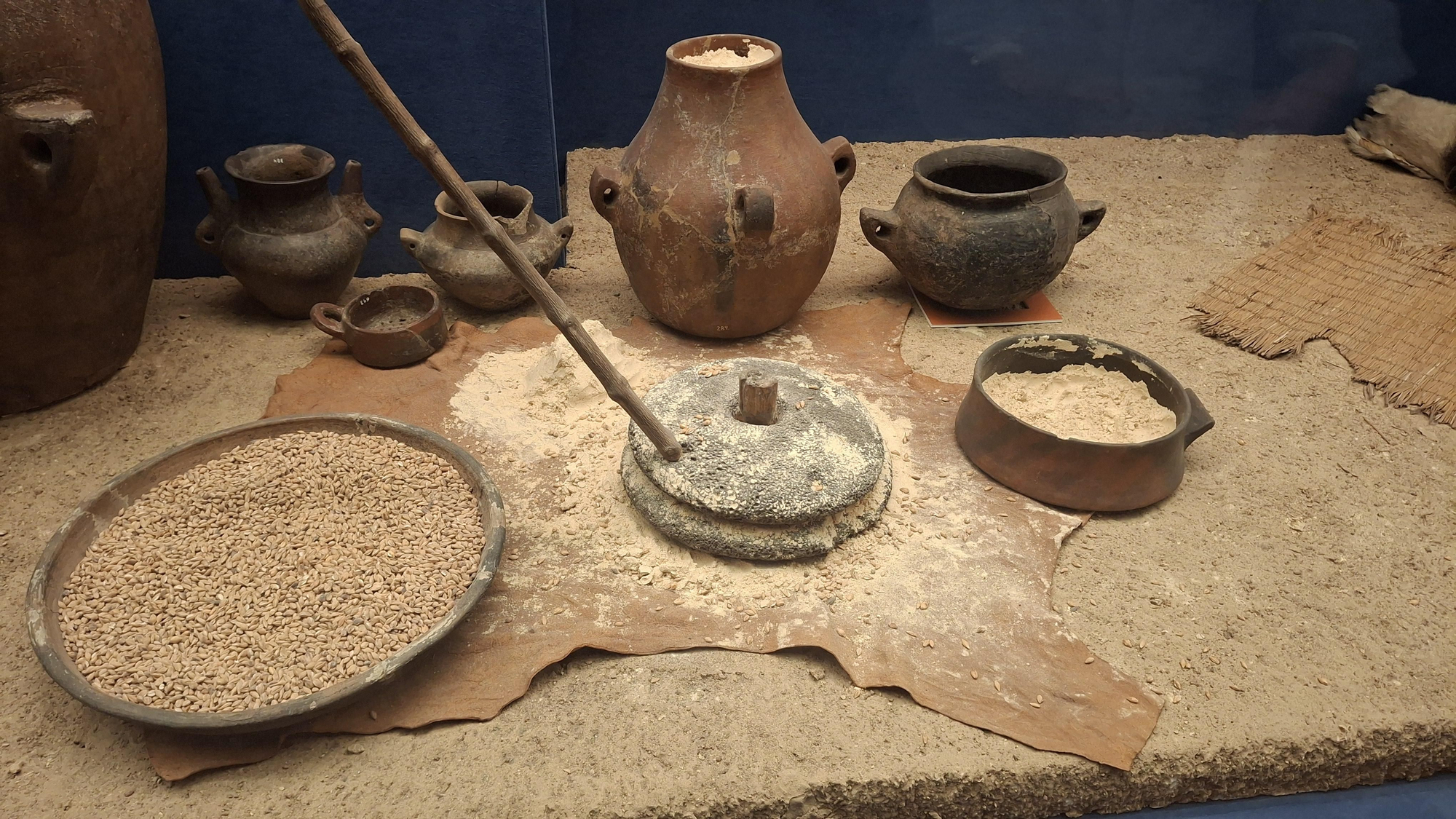 Este conjunto, expuesto en El Museo Canario, ilustra el proceso de elaboración del gofio: tostador de semillas de cebada, molino de mano y recipiente con la harina.