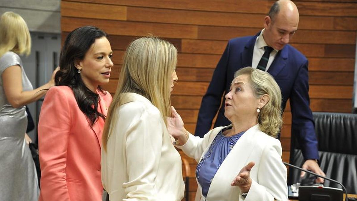 La consejera de Educación, Mercedes Vaquera, con los brazos abiertos, habla con la presidenta de la Junta, María Guardiola, en el pleno de este jueves