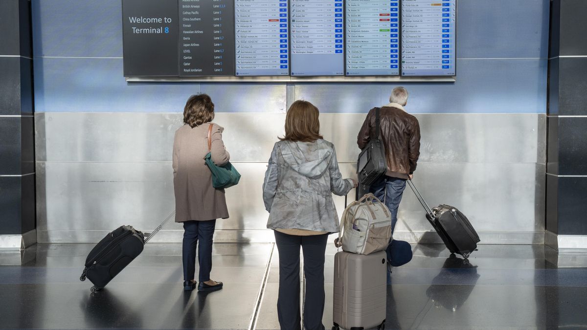 Varios pasajeros observan los monitores del aeropuerto John F. Kennedy este viernes, en Nueva York (EEUU).