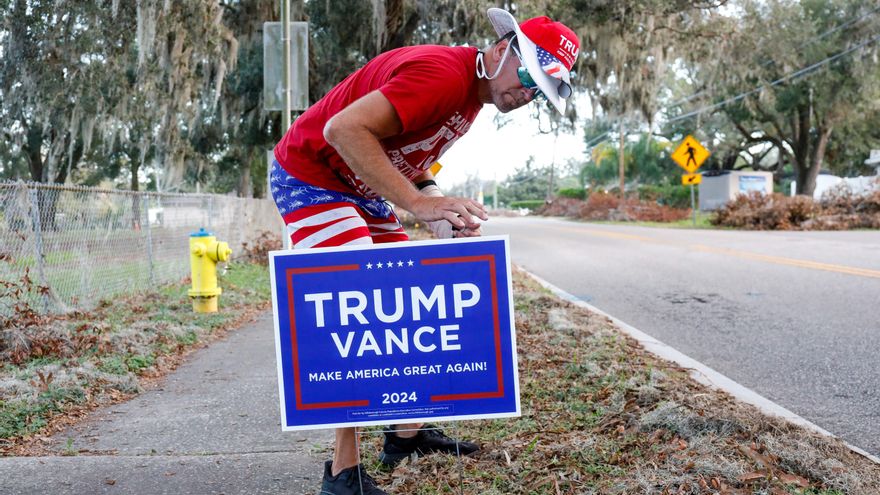 Un votante de Trump pone un cartel para pedir el voto por el candidato republicano.