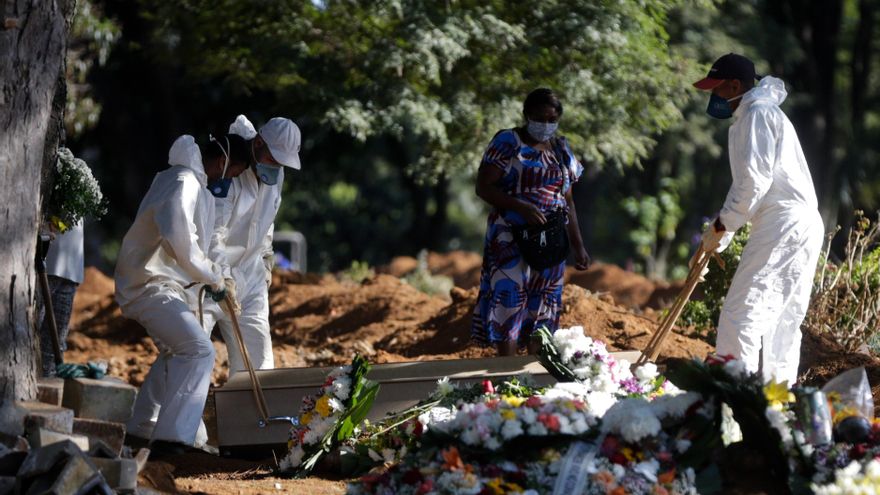 Empleados cargan el ataúd de una persona que murió por COVID-19 en el cementerio de Vila Formosa en Sao Paulo (Brasil). 
