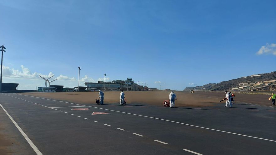 La ceniza del volcán afecta también a la operatividad del aeropuerto de La Palma. En la imagen, operarios limpiando la pista, llena de polvo