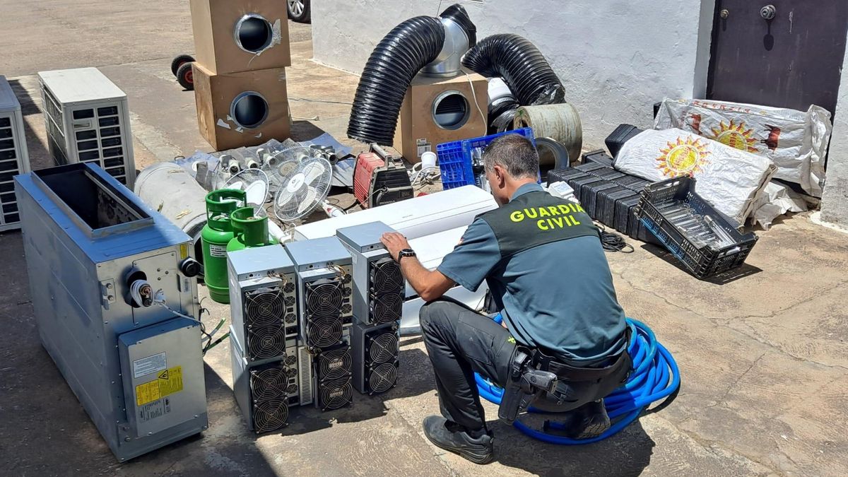 Un agente de la Guardia Civil, con la maquinaría utilizado en el taller de criptomonedas de Guillena.