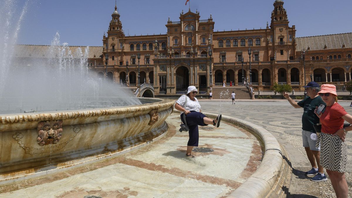 Imagen de turistas refrescándose en la fuente de la Plaza de España de Sevilla en agosto pasado. EFE/ Raúl Caro.