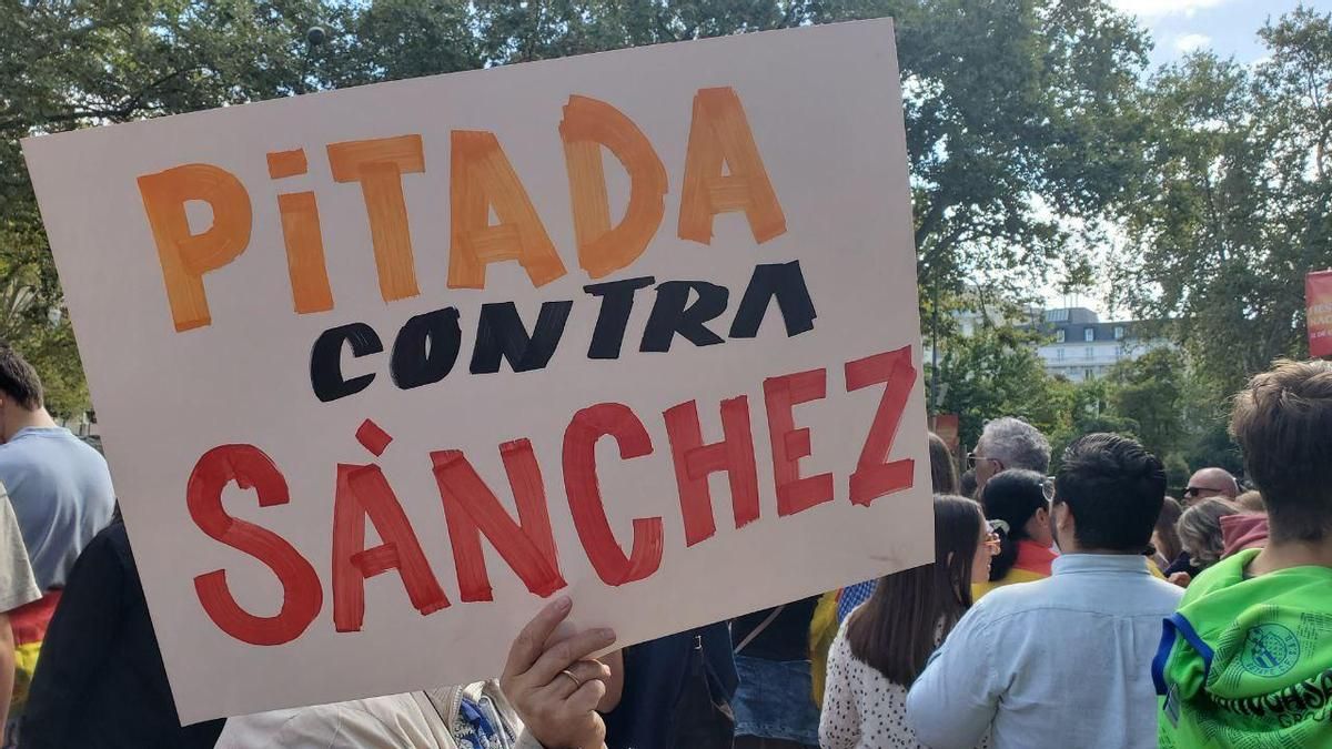 Un asistente al desfile porta un cartel en el que anima a pitar contra Pedro Sánchez