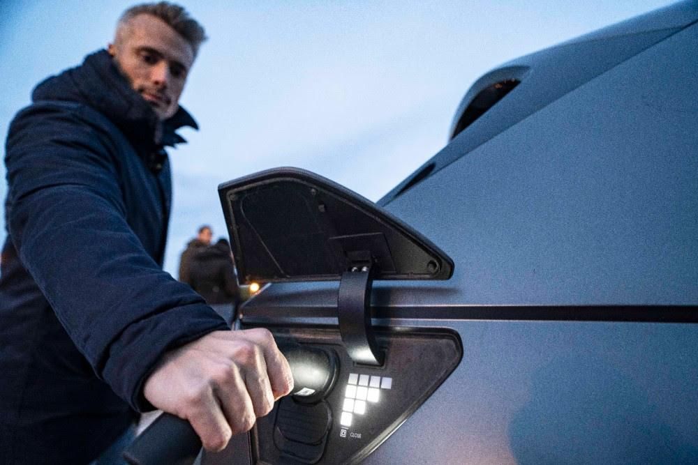 Una persona, realizando una recarga en un vehículo eléctrico.