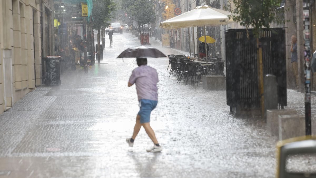 Una persona se protege de la lluvia, en una foto de archivo